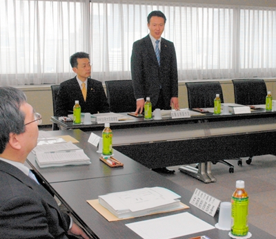 写真・図版 : ワーキングチームの初会合であいさつする加藤法務副大臣。隣の鈴木文科副大臣の席は空席だ